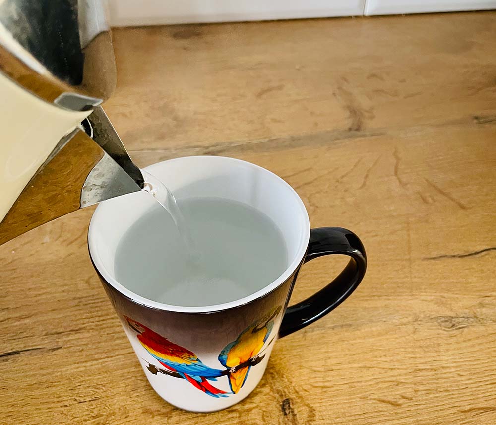 Kubek magiczny latte podczas nalewania gorącej wody
