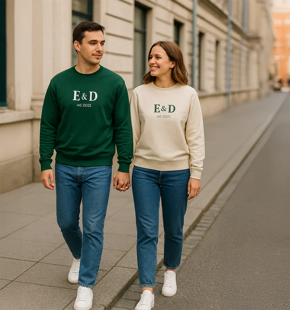 Para małżeńska w jeansach i białych sneakersach w bluzach z nadrukiem „E&D od 2021” – minimalistyczny duet podczas spaceru po mieście.