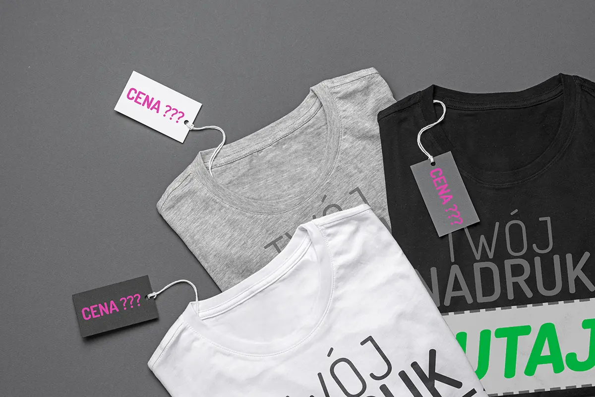 3 koszulki leżące na płaskiej powierzchni, każda z metką z napisem "CENA ???"