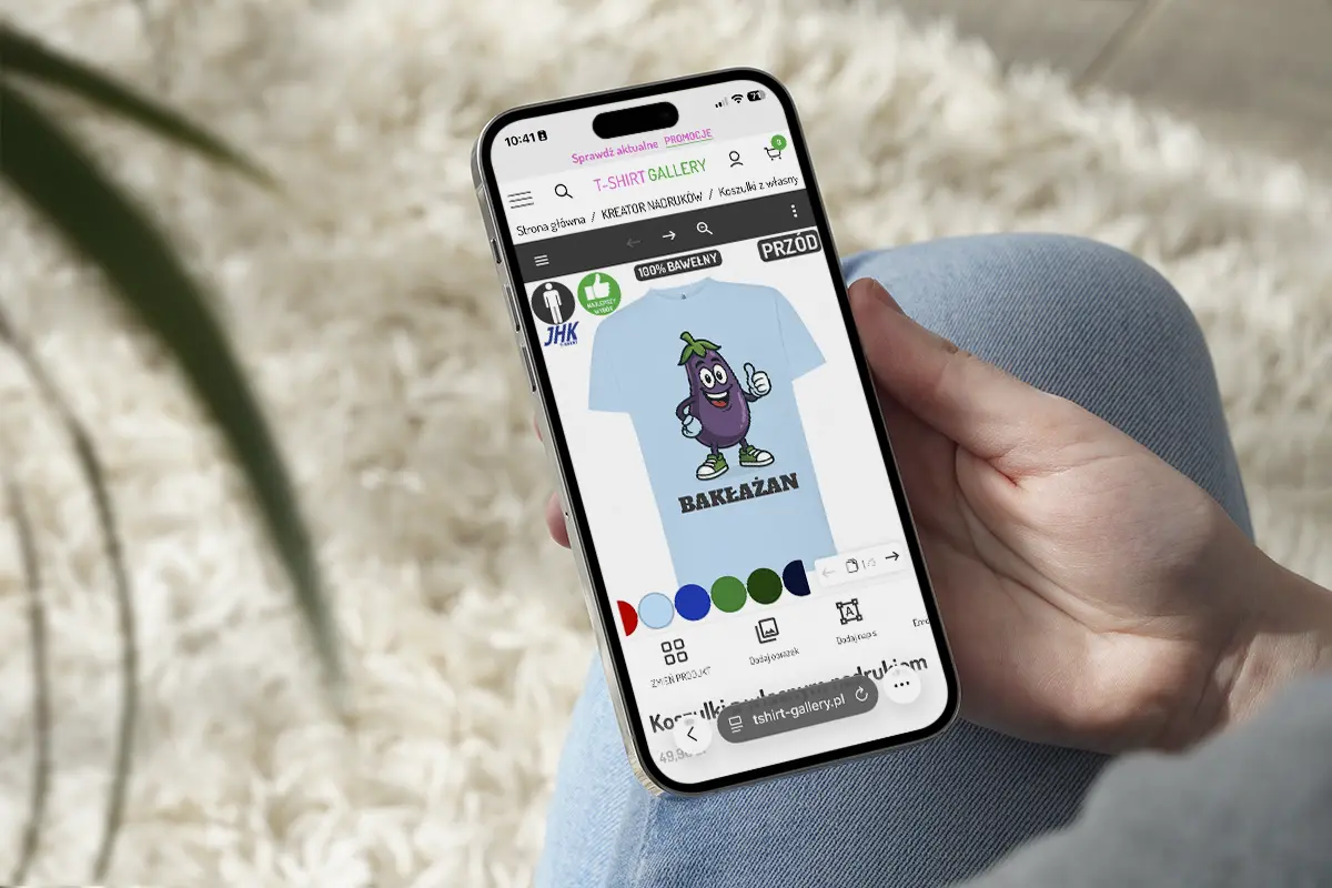 zbliżenie na rękę trzymającą telefon, na ekranie gotowy projekt koszulki w kreatorze nadruków
